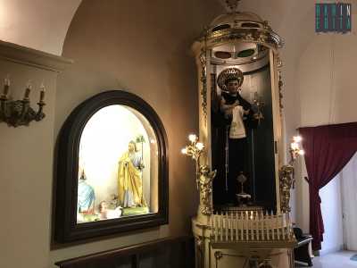 Ci spostiamo sul lato sinistro del tempio, ritrovandoci di fronte a una grande acquasantiera dalla forma insolitamente cilindrica, in cui si trova la statua in cartapesta di Sant'Antonio con in braccio Ges� bambino. L'edicola ha un tono sfarzoso, dettato dalle rifiniture dorate e illuminata da candeline laterali